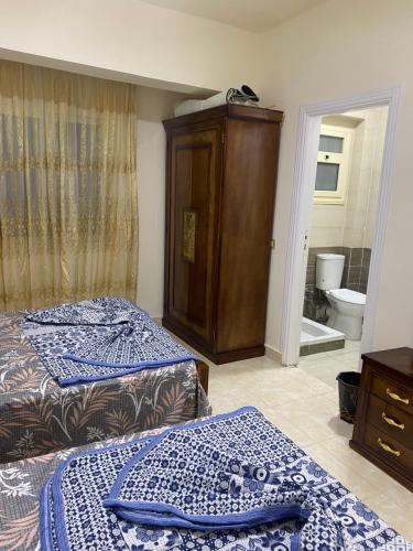 a bedroom with two beds and a cabinet and a toilet at تاهيتي باي الجراوله in Marsa Matruh