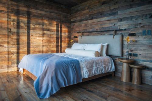 a bedroom with a bed in a wooden wall at Las Cabañas by PMJ in Cayambe