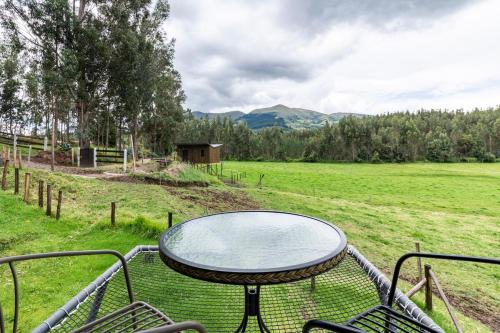 a patio with a table and chairs in a field at Las Cabañas by PMJ in Cayambe