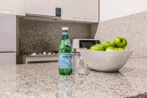 a bottle of soda sitting on a counter next to a bowl of apples at Punthill Apartment Hotel - Manhattan in Melbourne