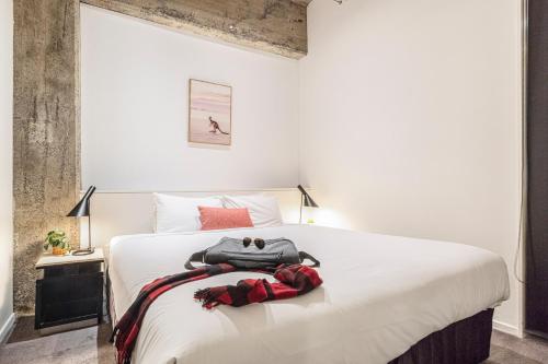a bedroom with a large white bed with two bags on it at Punthill Apartment Hotel - Manhattan in Melbourne