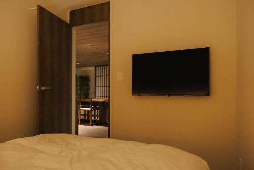 a bedroom with a flat screen tv on the wall at ONUJI stay in Busan