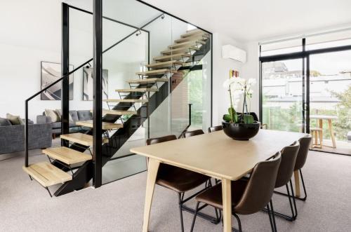 a dining room with a table and a staircase at Architectural Urban Diamond in Christchurch