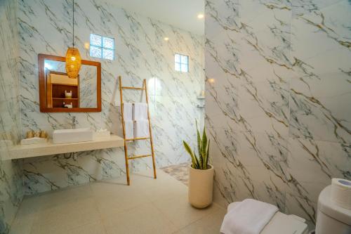 Un baño con una pared de mármol con un espejo y una escalera. en Villa Radha Seminyak, en Seminyak