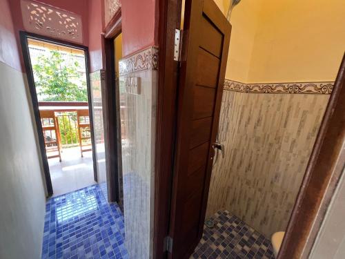 a bathroom with a shower and a door to a room at ERA Guest House in Ubud