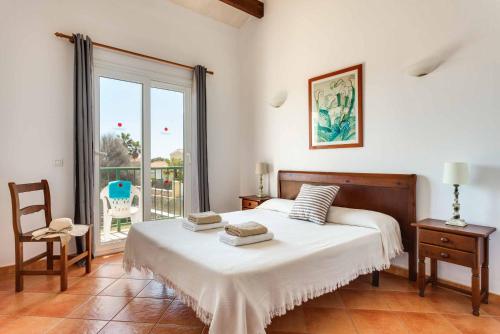 a bedroom with a bed and a chair and a window at Villa Aguasol in Cala en Forcat