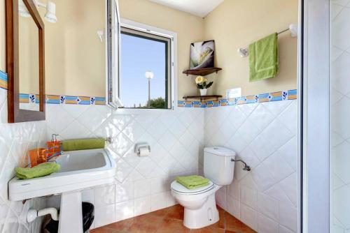 a bathroom with a sink and a toilet and a window at Villa Aguasol in Cala en Forcat