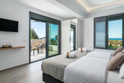 a bedroom with a bed and a tv and windows at Villa Summer Dawn in Kiotari