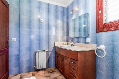 a blue tiled bathroom with a sink and a mirror at Villa Voltor Cinco in Pollença