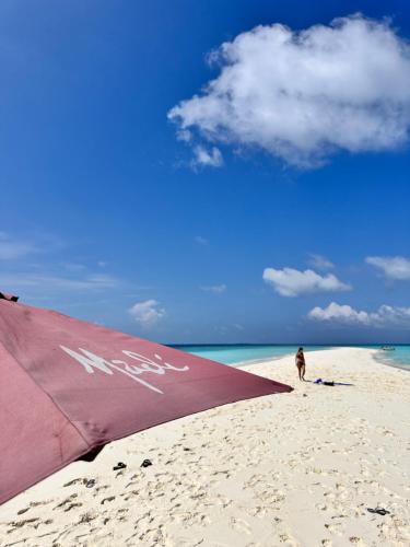 a person standing on a beach with a beach umbrella at Madi Beach Guesthouse in Maalhos