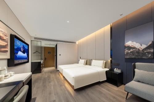 武漢市にあるAtour Hotel Wuhan Jianghan Road Jiangtanの白いベッドとテレビのある寝室