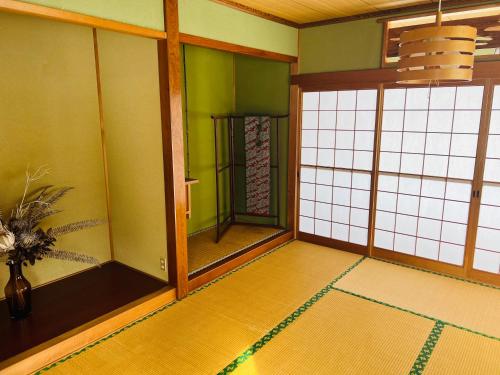 a japanese room with green walls and glass doors at ヴィラYukara緑屋 in Nanae