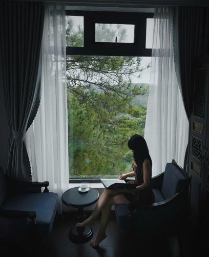 a woman sitting in a chair in front of a window at The Gate Boutique Hotel Đà Lạt in Da Lat