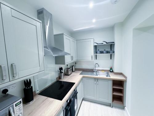 a white kitchen with white cabinets and a sink at The Octavius Apartment - Huntingdon Town Centre - Designed for Contractors & Professionals - Free WiFi - Smart TV - Fully Equipped Kitchen - Ideal for Long Work Stays in Huntingdon