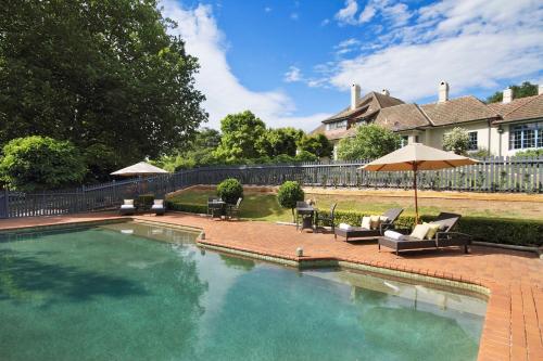 una piscina con sillas y sombrillas en un patio en Peppers Manor House, en Sutton Forest