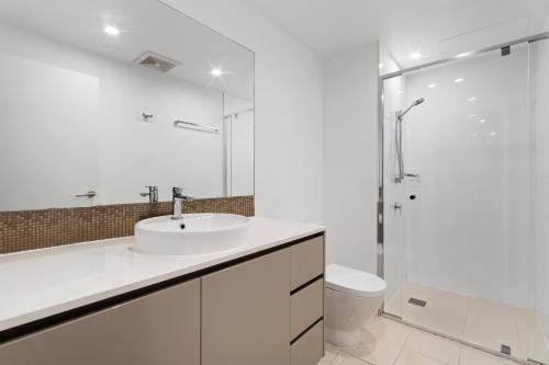 a white bathroom with a sink and a shower at Amazing Ocean View Apartment in Surfers Paradise in Gold Coast
