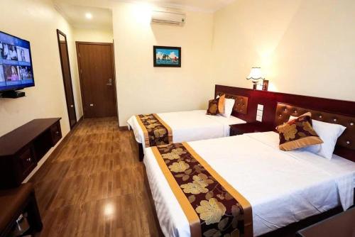 Una habitación de hotel con dos camas y un televisor de pantalla plana. en Ha Long Lotus Hotel, en Ha Long