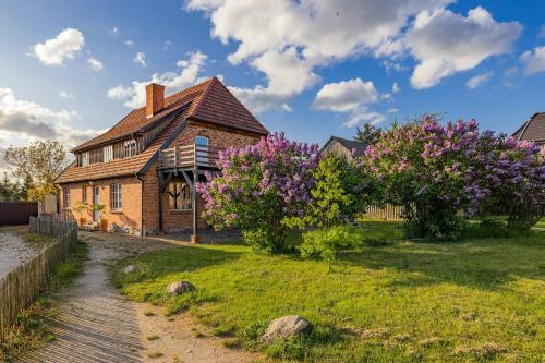 a brick house with purple flowers in the yard at Spacious Vacation Apartment With A Garden View in Walow