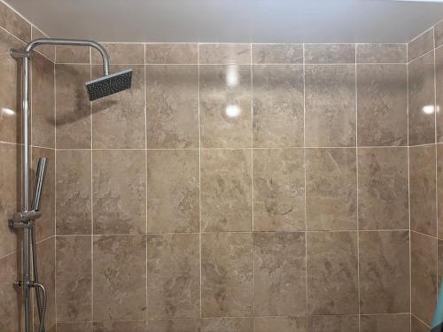 a bathroom with a shower with a tile wall at The Olive Villa in Manchester