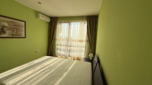 a green room with a bed and a window at Двустаен апартамент с прекрасна морска гледка и голяма тераса на самия бряг на морето in Elenite
