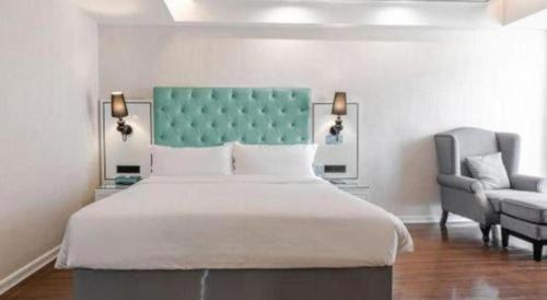 a bedroom with a large bed and a chair at Xana Lite Anqing Yuexi Swan Squre Branch in Yuexi