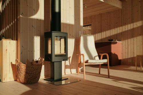 a living room with a fireplace and a chair at Designer Cabin By Lake Nisser With View And Sauna in Treungen
