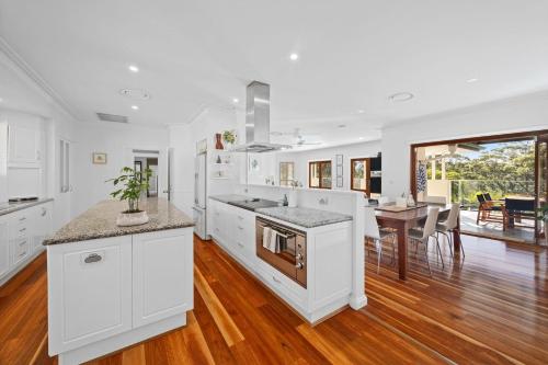 a kitchen with white cabinets and a dining room at Ridge Retreat in Mollymook
