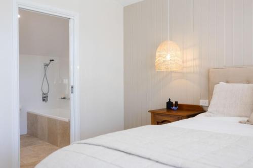 a white bedroom with a bed and a bath tub at Ridge Retreat in Mollymook