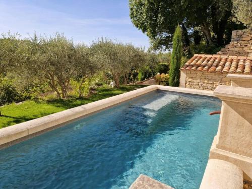une piscine à débordement dans une cour arrière avec des arbres et une maison dans l'établissement Cozy House In The Heart Of Provence, à La Roque-sur-Pernes
