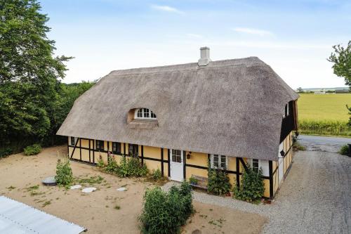 an old house with a thatched roof at Nostalgic Charm In A Yellow Timber House in Sakskøbing