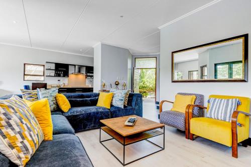 a living room with a blue couch and yellow chairs at Baluwatu 10, Zimbali Estate by Euphoric Leisure in Ballito