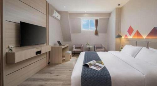 a hotel room with a bed and a flat screen tv at Borrman Hotel Yuxi Yuxing Road in Yuxi