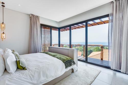 ein Schlafzimmer mit einem Bett und einem großen Fenster in der Unterkunft Oceans Edge 13, Zimbali Estate by Euphoric Leisure in Ballito