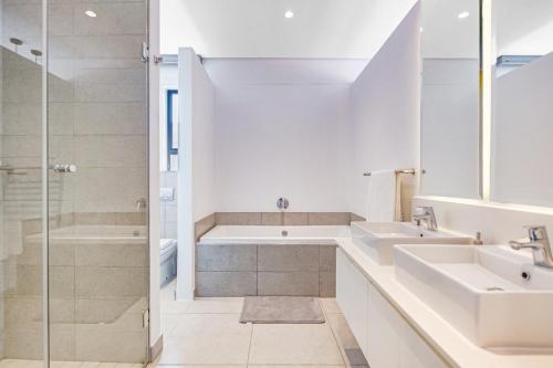 ein weißes Badezimmer mit zwei Waschbecken und einer Dusche in der Unterkunft Oceans Edge 13, Zimbali Estate by Euphoric Leisure in Ballito