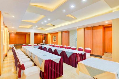 a banquet hall with white tables and red chairs at Palette Hotel Nisarga by Sunday Bhopal in Bhopal