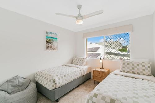 Un dormitorio con dos camas y una ventana. en By The C, en Gold Coast