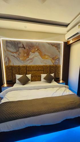 a bedroom with a large bed with a painting on the wall at Aura Stays in Lucknow