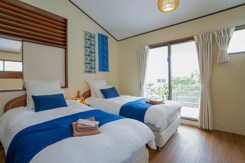 two beds in a room with two windows at Peace Branch in Yonabaru