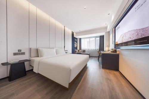 a bedroom with a large white bed and a desk at Atour Hotel Shenyang Tiexi Plaza Qigong Street Subway Station in Shenyang