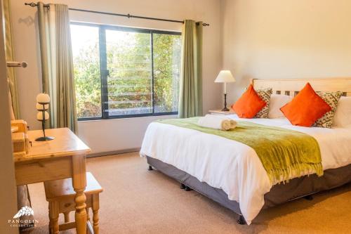 a bedroom with a bed with orange pillows and a window at Aleah, Cathkin Estates by Euphoric Leisure in Champagne Valley