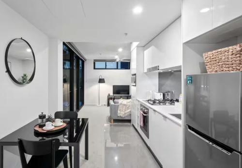 Una cocina blanca con una mesa y un refrigerador. en The Perfect Location Gym, Pool & Parking M22, en Brisbane
