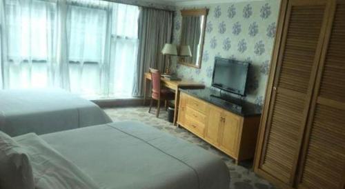 a hotel room with a bed and a desk with a television at New Pearl River Hotel in Guangzhou