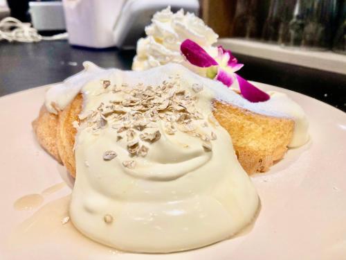 a piece of cake with a flower on a white plate at Ma-Blue Garden House in Motobu