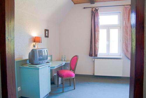 a room with a desk with a tv and a chair at Gasthof Schloss Hubertus in Erfurt
