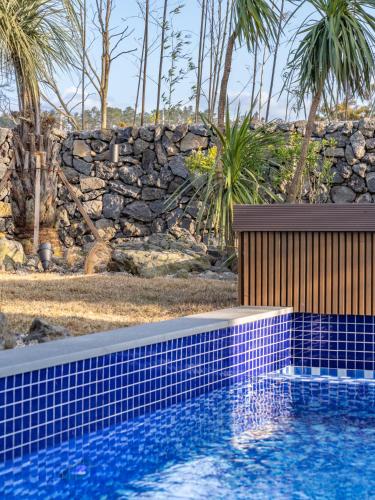 a swimming pool in front of a stone wall at Gobajinin Private Pool Villa in Jeju