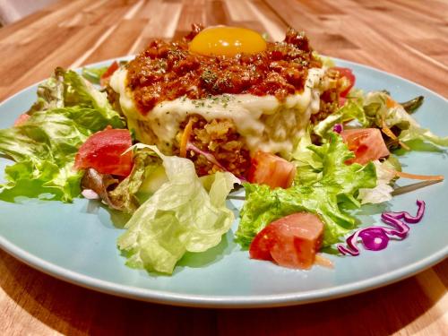 a plate of food with an egg and salad on a table at Ma-Blue Garden House in Motobu