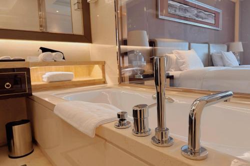 a bathroom with a bath tub and a bed at Wanda Realm Dandong in Dandong