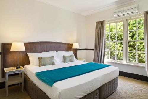 a bedroom with a large bed with a blue blanket at Peppers Manor House in Sutton Forest