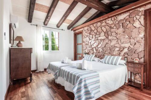 a bedroom with two beds and a stone wall at Bell Veure in Ciutadella
