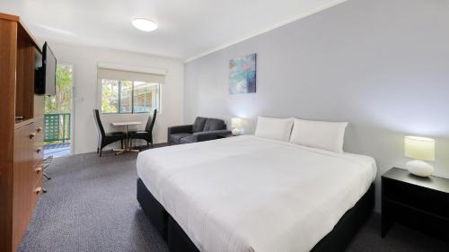 a bedroom with a large white bed and a desk at Best Western Cattle City Motor Inn in Rockhampton
